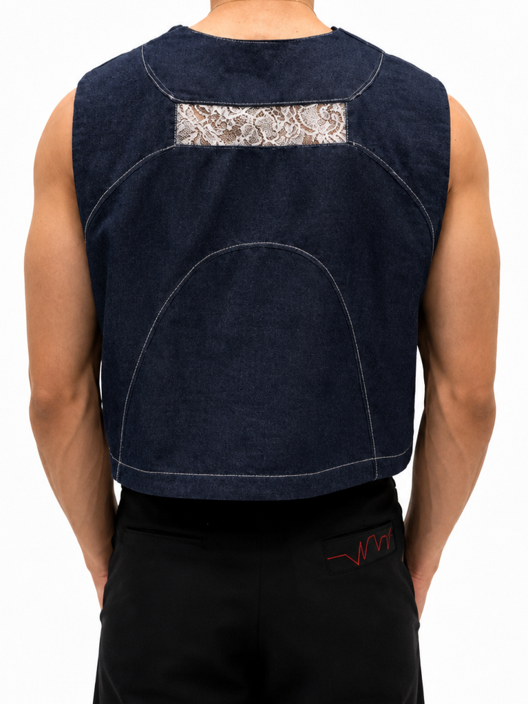 Back view of a sleeveless cropped tank top in dark indigo denim, featuring a decorative beige and white paisley lace panel across the upper back, worn by a model.