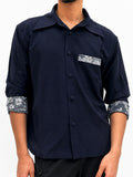 A man wearing a dark navy blue button-up shirt with contrasting light gray and white floral patterned cuffs and a matching chest pocket band. Front view of navy oversized overshirt with floral lace chest pocket detail, lace cuffs, and concealed button placket.